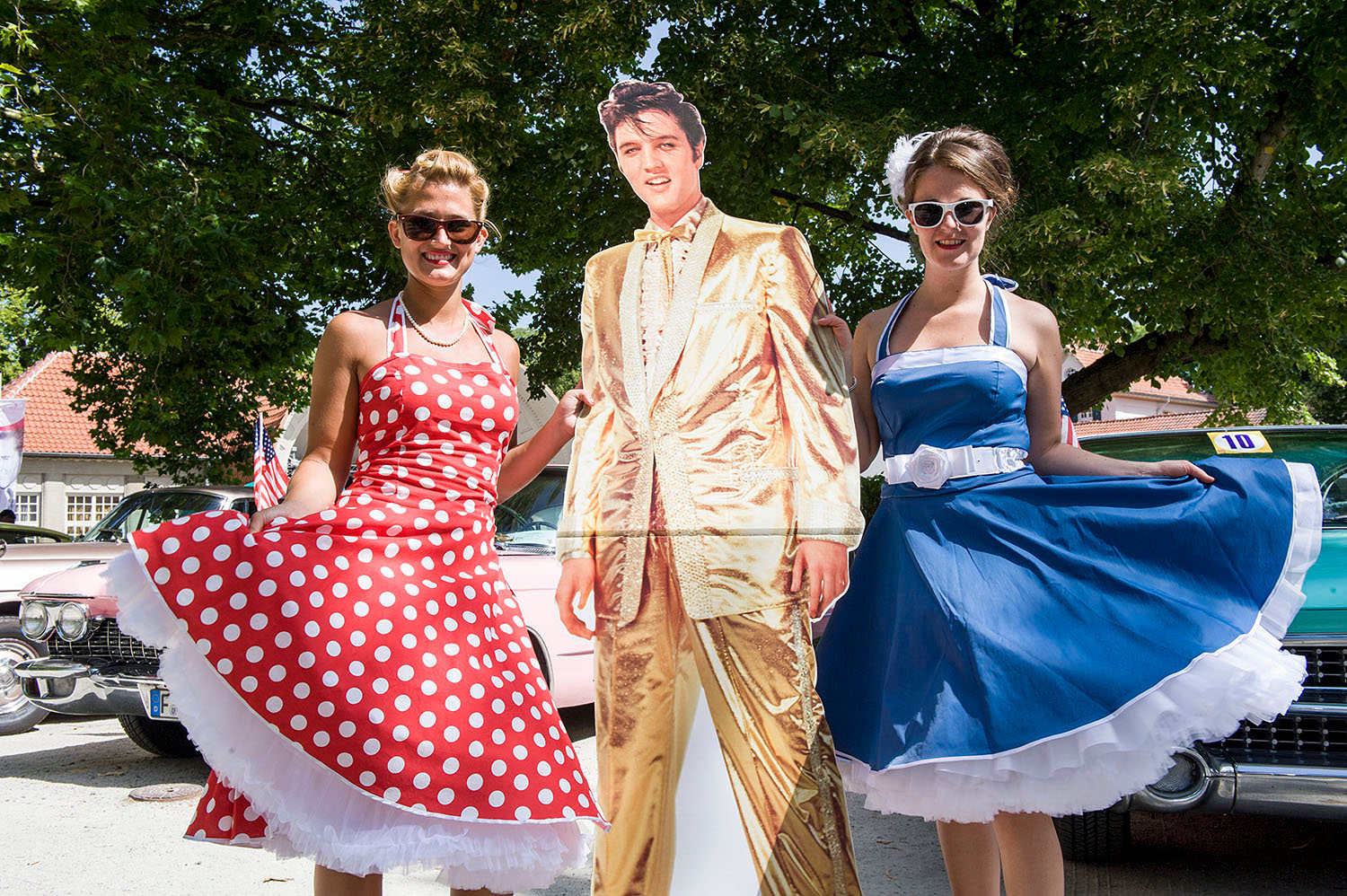 Zwei junge Frauen im Petticoat, halten eine Elvis-Pappfigur in den Händen